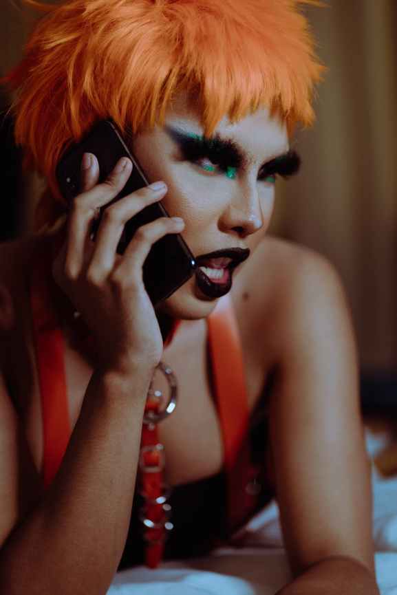 extravagante jeune femme ethnique en tenue excentrique parlant au telephone mobile dans la chambre