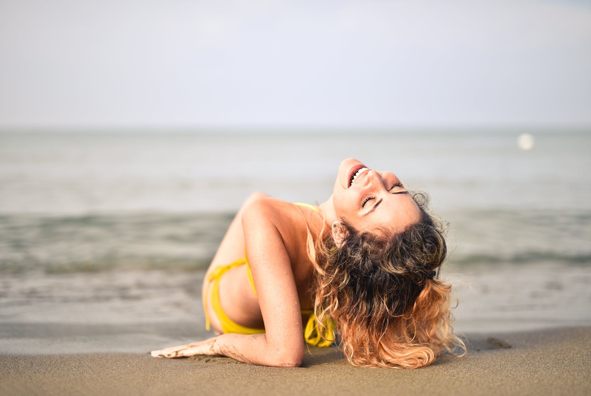 femme en bikini jaune allonge sur le bord de mer