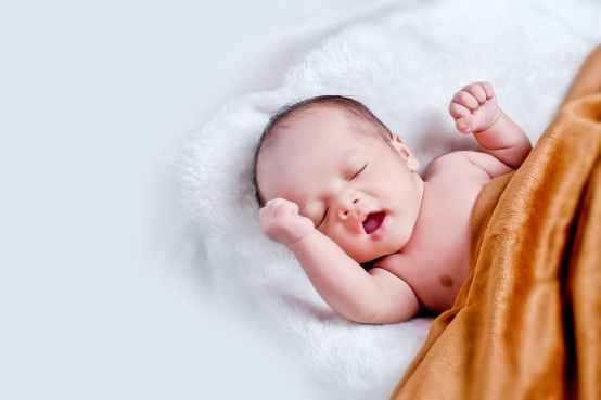 bebe couche sur une fourrure blanche avec une couverture marron
