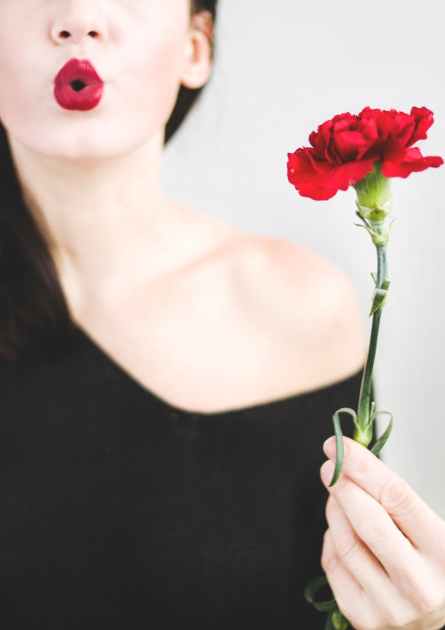 photo d une femme tenant une fleur d oeillet rouge